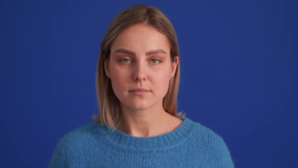 Przystojna Pozytywna Kobieta Niebieskim Swetrze Patrząca Kamerę Niebieskim Studio — Wideo stockowe