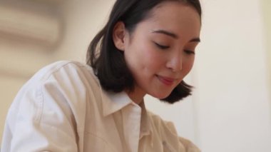 Yakışıklı Asyalı kadın evde bir şeyler yazıyor.