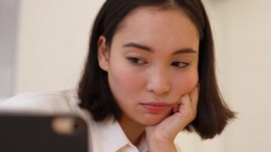 Uzaktan eğitim gören üzgün Asyalı kadın evde tabletten öğreniyor.