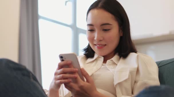 Sebevědomý Asijské Žena Smskování Telefonu Pohovce — Stock video