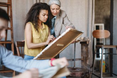 Sanat okulunda ders sırasında öğrencisiyle konuşan olgun bir öğretmen.