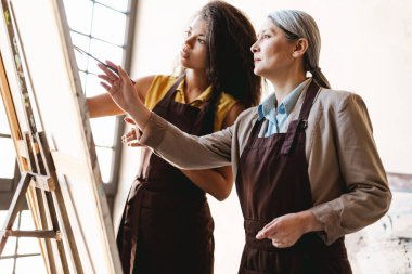 Sanat okulunda ders sırasında öğrencisiyle konuşan olgun bir öğretmen.
