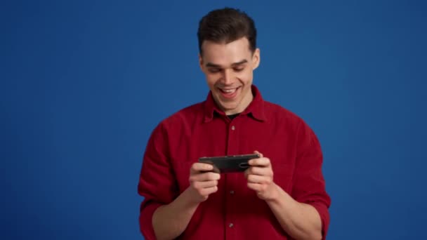 Γελώντας Brunet Άνθρωπος Παίζει Ψηφιακό Παιχνίδι Στο Τηλέφωνο Στο Μπλε — Αρχείο Βίντεο
