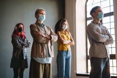 Yüz maskesi takmış çok kültürlü bir adam ve kadın içeride dikilirken yan yan bakıyor.