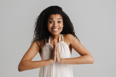 Avuç içlerini bir arada tutan siyah genç kadın beyaz arka planda izole edilmiş kameraya bakıyor.