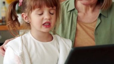 Pozitif büyükanne ve torun mutfaktaki tabletten bir şey izliyor.