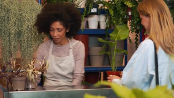 アフリカの女性の花屋は屋内で顧客と話して笑顔 — ストック動画