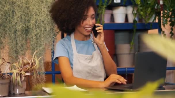 Handsome African Female Florist Talking Phone Looking Laptop Indoors — Stock Video