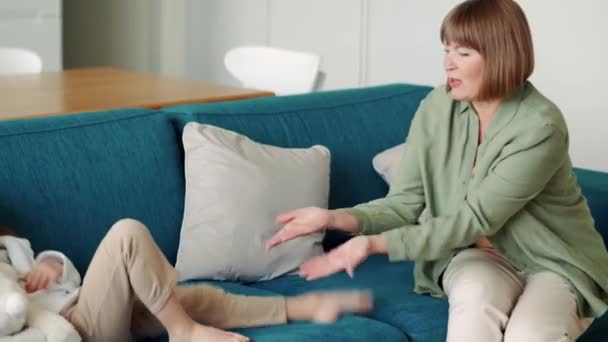 Усміхнена Бабуся Міняє Ноги Своїй Онуці Дивані — стокове відео