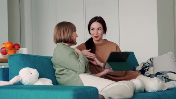 Smiling Mother Watching Something Tablet Talking Daughter Sofa — Stock Video