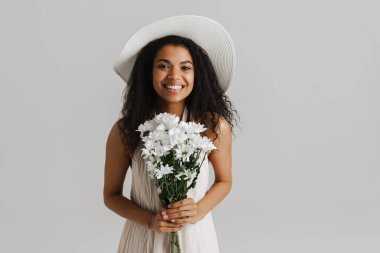 Şapkalı genç bir kadın kasımpatı ile poz veriyor. Beyaz arka planda izole edilmiş.