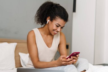 Mutlu, genç Afrikalı bir kadın yatak odasında oturuyor.