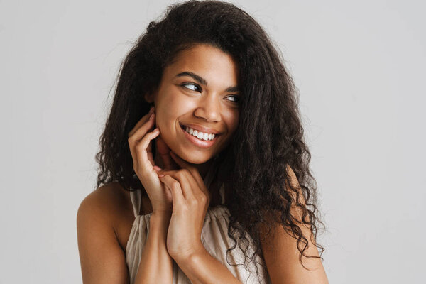 Black young woman in dress smiling and looking aside isolated over white background