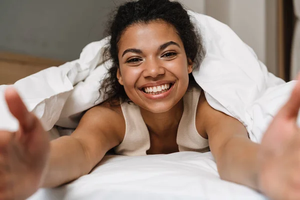 Счастливая Молодая Африканская Женщина Лежала Одеялом Кровати Дома Смеялась Вытянутыми — стоковое фото