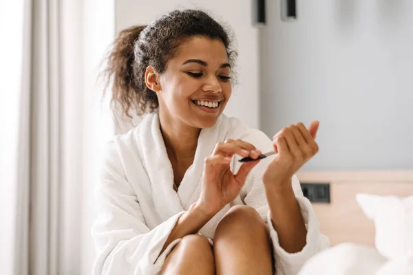 Sorridente Giovane Donna Africana Accappatoio Seduta Letto Limatura Unghie Camera — Foto Stock