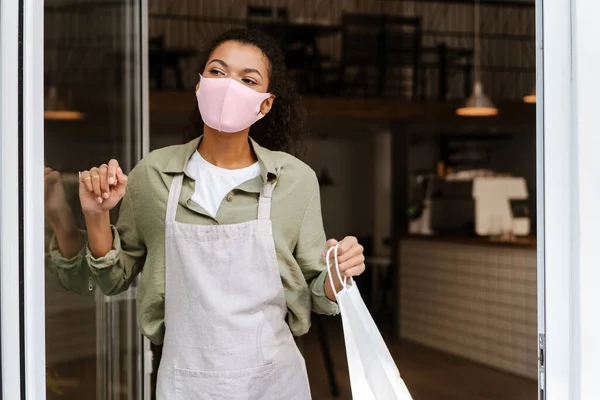 Empregada Mesa Preta Usando Máscara Facial Segurando Saco Papel Enquanto — Fotografia de Stock