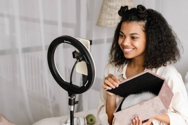 Siyah kadın cep telefonundan selfie çekerken kutu gösteriyor.