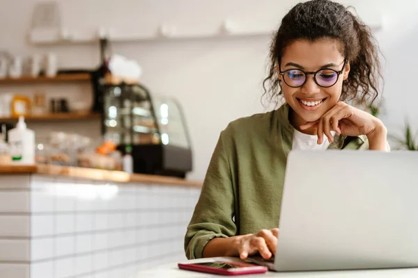 Gözlüklü Genç Siyahi Kadın Kafede Otururken Dizüstü Bilgisayarla Çalışıyor — Stok fotoğraf