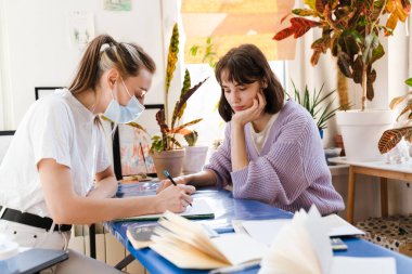 Genç beyaz iki kadın evde otururken birlikte çalışıyor.