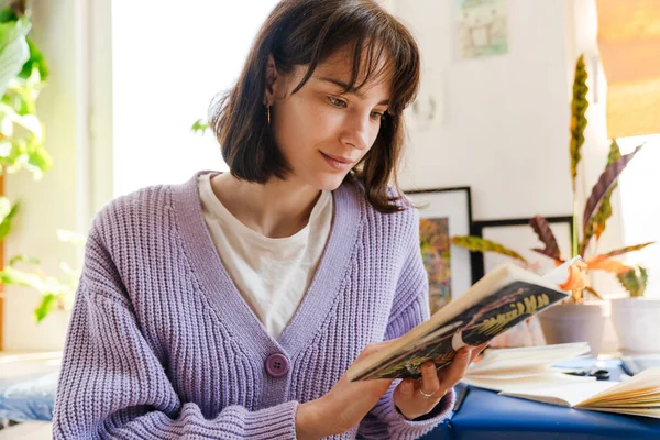 Mujer Blanca Joven Mirando Cuaderno Bocetos Mientras Está Sentado Interior —  Fotos de Stock