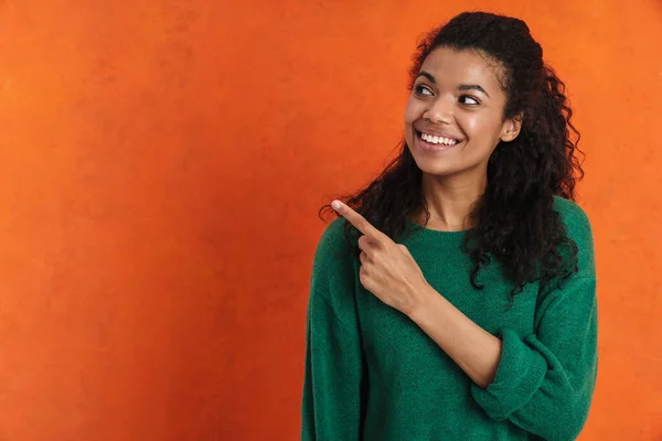 幸せな若いですアフリカ人女性でカジュアルな着用上のオレンジの背景 指差し指脇にコピースペース — ストック写真