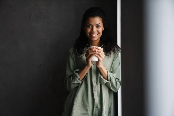 Svart Ung Kvinne Smiler Mens Hun Drikker Kaffe Inne – stockfoto