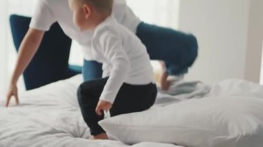 Neşeli anne ve oğul evdeki yatakta zıplıyorlar.