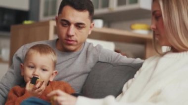 Neşeli bir aile evdeki kanepede oturup konuşuyor.