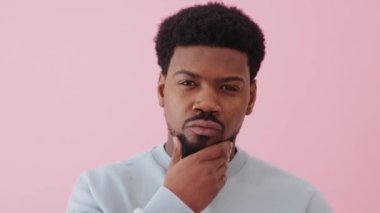 Yakışıklı Afrikalı adam pembe stüdyodaki kameraya bakışını düzeltiyor.