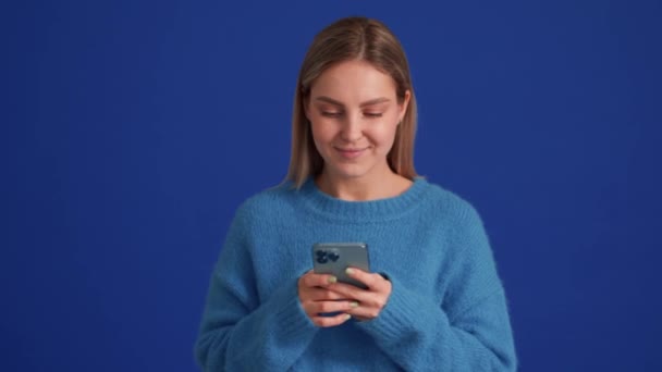 Pozitivní Žena Sobě Modrý Svetr Textování Telefonem Modrém Studiu — Stock video