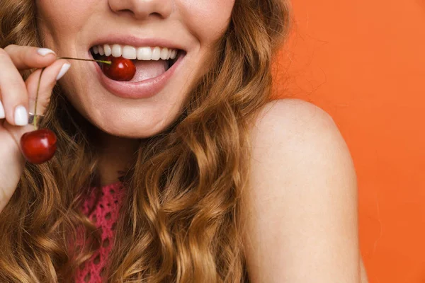 年轻的金银花女微笑着吃着橘子墙上的樱桃 — 图库照片