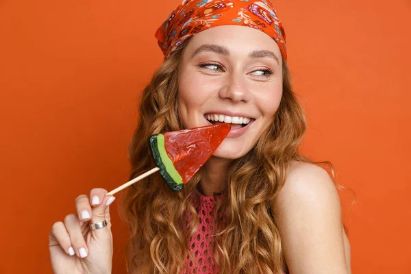 Joven Pelirroja Vistiendo Bandana Sonriendo Mientras Lame Piruleta Aislada Sobre —  Fotos de Stock