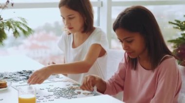 İki yakışıklı çoklu etnik kız kardeş evde yapboz yapıyor.