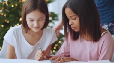 İki gülen çoklu etnik kız kardeş evde bir şeyler yazıyor.