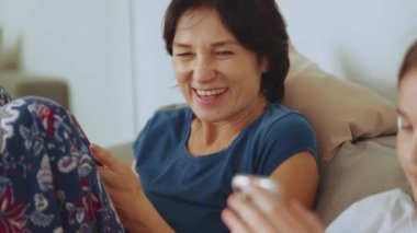 Gülümseyen anne evde kızının telefonuna bakıyor.