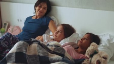 Yatakta konuşan çok ırklı yakışıklı bir aile.
