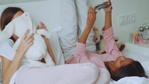 Neşeli Çoklu Etnik Kız Kardeşler Evdeki Yatakta Telefonla Selfie Çekiyorlar — Stok video