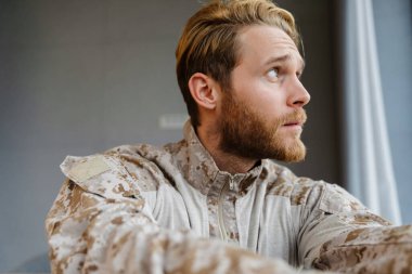 Üniformalı, kendinden emin erkek asker içeri bakıyor.