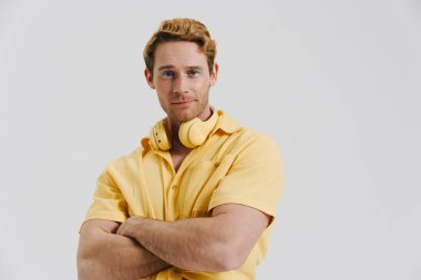 Kulaklıklı, beyaz duvarın üzerinden izole edilmiş kameraya bakan kızıl saçlı genç adam.