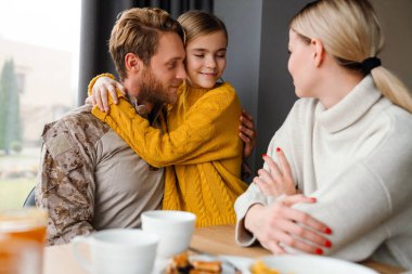 Güzel, mutlu bir aile kahvaltısı yaparken konuşuyor ve sarılıyor.