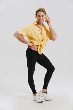 Kızıl, genç adam gülümseyen ve dinleyen kulaklıklarla beyaz duvarın üzerinden izole edilmiş.