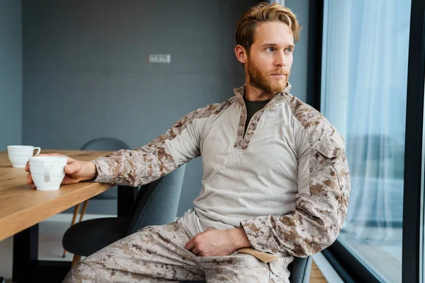 Masculino Confiado Militar Bebiendo Café Mientras Está Sentado Mesa Casa — Foto de Stock