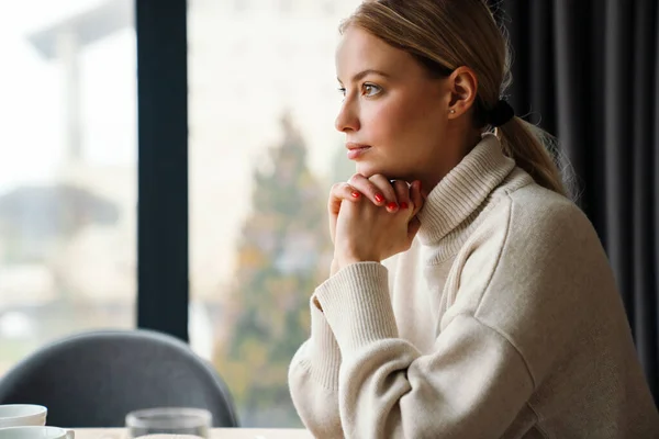 Mooi Denkende Vrouw Kijkt Vooruit Terwijl Zitten Aan Tafel Binnen — Stockfoto