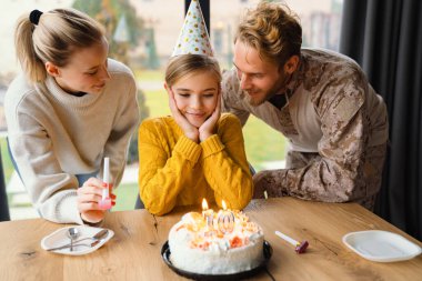 Güzel, mutlu bir aile evde kızının doğum gününü kutlarken gülüyor.
