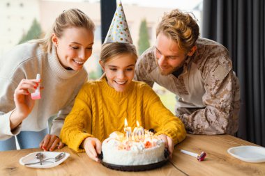 Güzel, mutlu bir aile evde kızının doğum gününü kutlarken gülüyor.