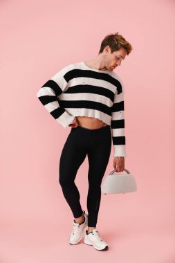 Külotlu çorap giyen genç bir adam pembe duvarın üzerinden izole edilmiş halterle poz veriyor.