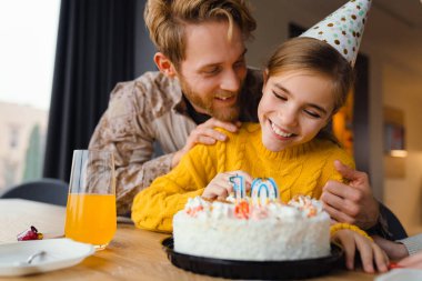 Güzel, neşeli, beyaz bir baba ve kızı evde doğum gününü kutluyor.