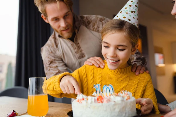 Güzel, neşeli beyaz bir aile, kızının doğum gününü evde kutluyor.