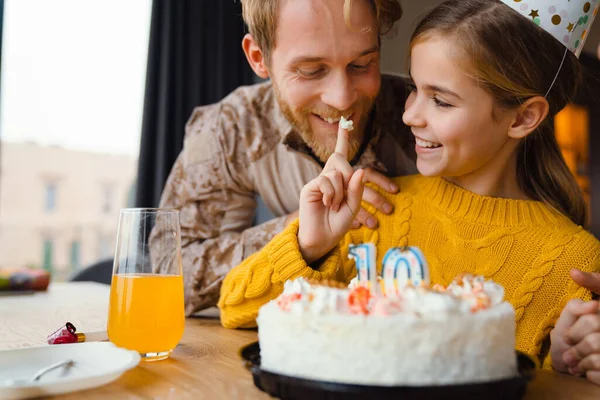 Güzel, neşeli beyaz bir aile, kızının doğum gününü evde kutluyor.