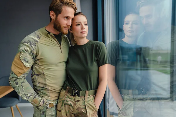 Güzel, genç, asker bir çift kucaklaşıp pencereden dışarı bakıyor.
